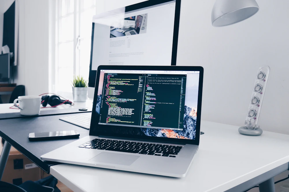 Laptop on a clean white desk displaying code