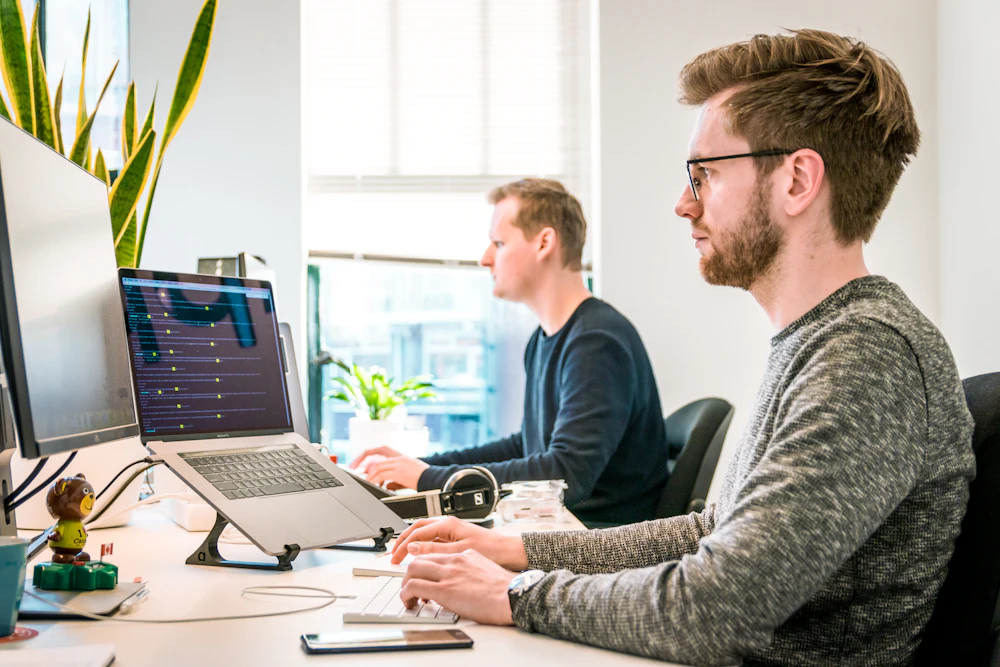 Two developers working at monitors in a bright office