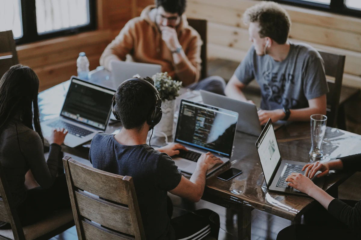 Team working together on laptops around a wooden table