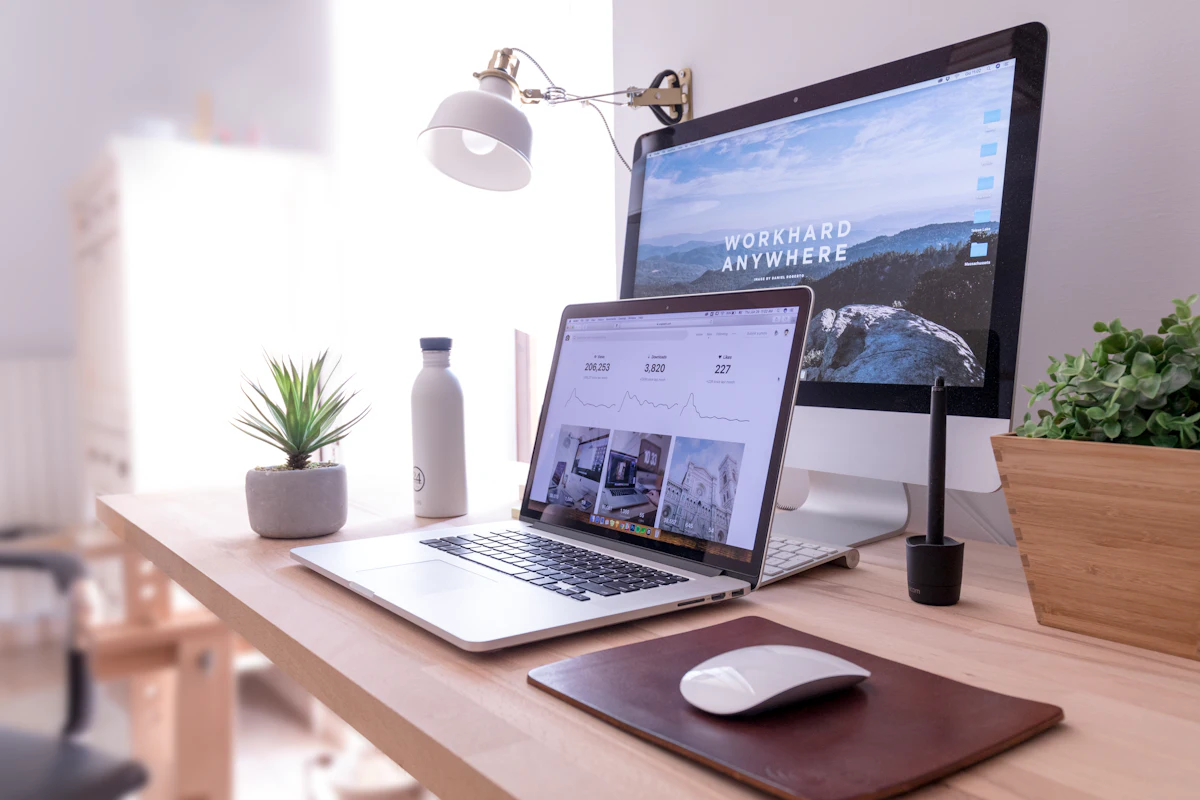 A website design shown across a monitor and laptop on a bright desk